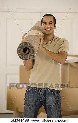 Stock Photo - Man holding rolled rug in new house. Fotosearch