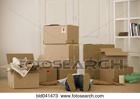 Stock Image - Man laying on floor next to moving boxes. Fotosearch