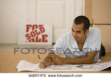 Man writing on blueprints in new house View Large Photo Image Stock Photography - Man writing on blueprints in new house. Fotosearch