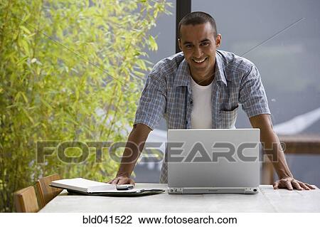 Portrait of young man with laptop View Large Photo Image Stock Image - Portrait of young man with laptop. Fotosearch