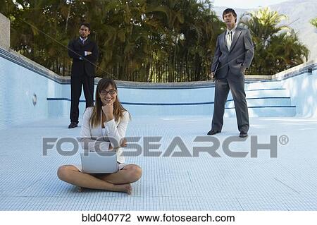 Stock Image - South American businesspeople in empty swimming pool. Fotosearch
