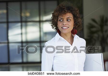 Stock Image - South American businesswoman holding laptop. Fotosearch