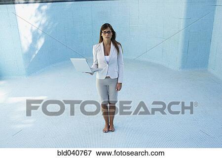 Stock Photo - South American businesswoman in empty swimming pool. Fotosearch