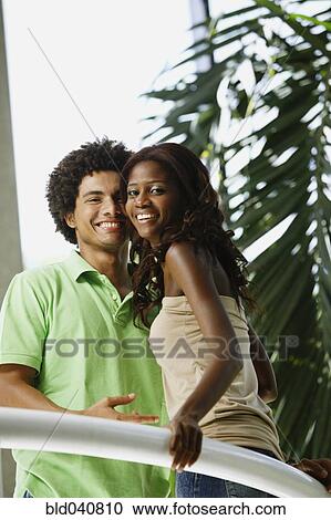 Stock Image - South American couple leaning on railing. Fotosearch