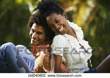 Stock Image - South American couple sitting back to back. Fotosearch
