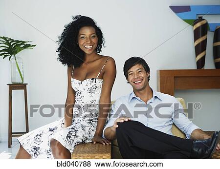 Stock Photo - South American couple sitting on chair. Fotosearch
