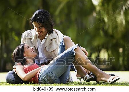 Stock Photo - South American couple sitting on grass. Fotosearch