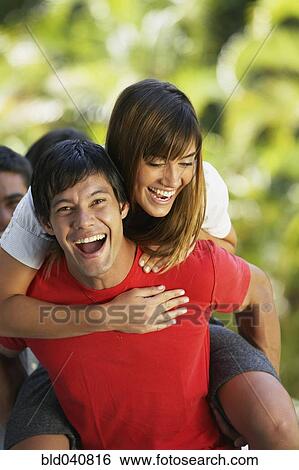 Stock Photograph - South American man giving girlfriend piggyback ride. Fotosearch