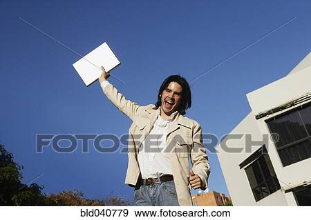 South American man holding laptop over head View Large Photo Image Stock Photo - South American man holding laptop over head. Fotosearch