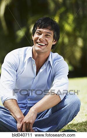 Stock Image - South American man sitting in grass. Fotosearch