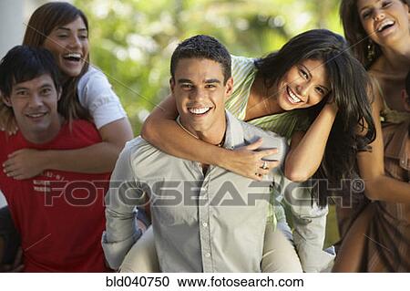 Stock Image - South American men giving girlfriends piggyback rides. Fotosearch