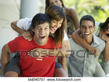 Stock Image - South American men giving girlfriends piggyback rides. Fotosearch