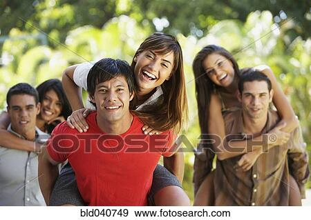 Stock Photo - South American men giving girlfriend’s piggyback rides. Fotosearch