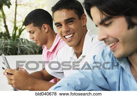 Stock Photo - South American men using cell phones. Fotosearch