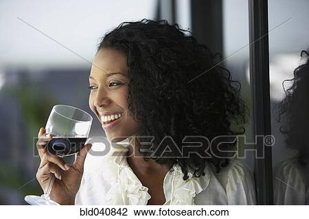 Stock Image - South American woman drinking wine. Fotosearch