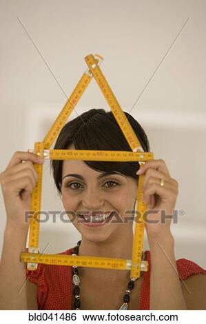 Stock Photograph - Woman holding folding ruler shaped like house. Fotosearch