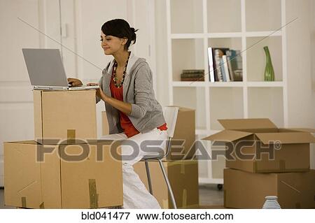 Stock Photo - Woman using laptop in new house. Fotosearch