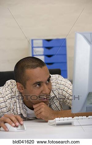 Young businessman looking at computer View Large Photo Image Stock Image - Young businessman looking at computer. Fotosearch