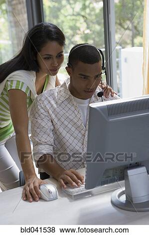 Stock Photo - Young businesspeople looking at computer. Fotosearch