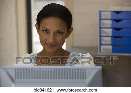 Stock Image - Young businesswoman sitting at computer. Fotosearch