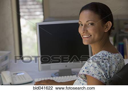 Stock Image - Young businesswoman sitting at computer. Fotosearch