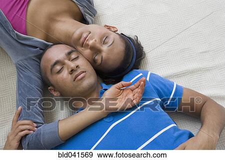Stock Photo - Young couple laying with heads touching. Fotosearch
