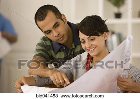 Young couple looking at blueprints in new house View Large Photo Image Stock Photo - Young couple looking at blueprints in new house. Fotosearch