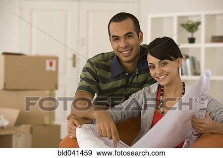 Young couple looking at blueprints in new house View Large Photo Image Stock Photo - Young couple looking at blueprints in new house. Fotosearch