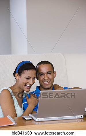 Young couple looking at laptop View Large Photo Image Stock Image - Young couple looking at laptop. Fotosearch