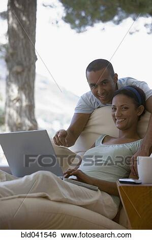 Stock Photograph - Young couple looking at laptop. Fotosearch