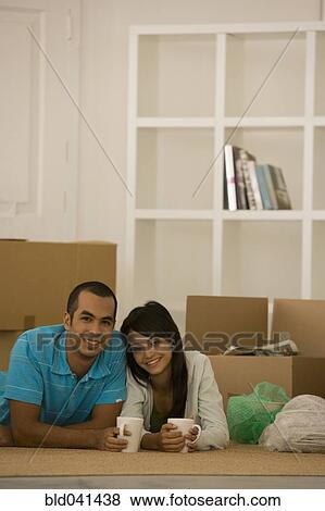 Stock Photo - Young couple next to unpacked moving boxes. Fotosearch