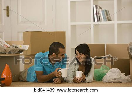 Stock Photo - Young couple next to unpacked moving boxes. Fotosearch