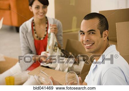 Stock Photo - Young couple packing moving boxes. Fotosearch