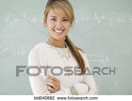 Stock Image - Young Hispanic woman in front of blackboard. Fotosearch