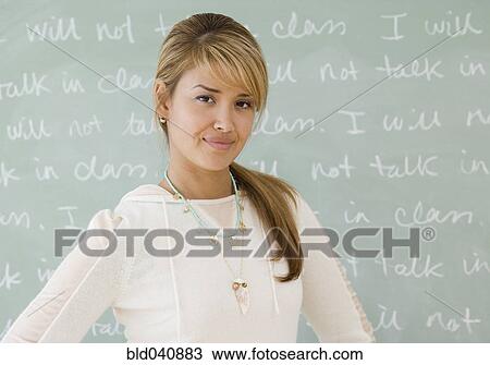 Stock Image - Young Hispanic woman in front of blackboard. Fotosearch
