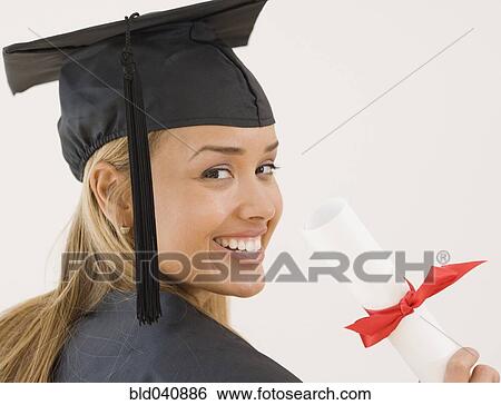 Stock Photograph - Young Hispanic woman wearing graduation cap and gown. Fotosearch