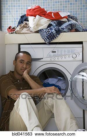 Stock Image - Young man doing laundry. Fotosearch