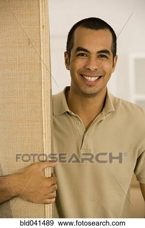Stock Photo - Young man holding rolled rug. Fotosearch