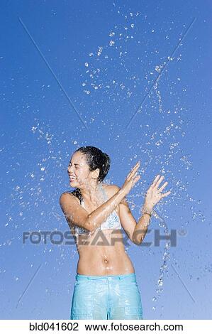 Stock Image - Young woman being splashed. Fotosearch