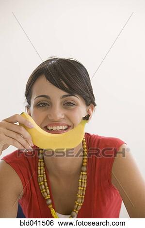 Stock Photograph - Young woman holding banana. Fotosearch