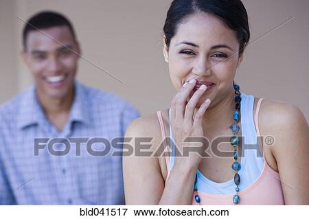 Stock Photo - Young woman laughing with boyfriend in background. Fotosearch
