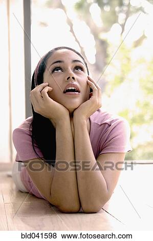 Stock Photo - Young woman laying on floor looking up. Fotosearch