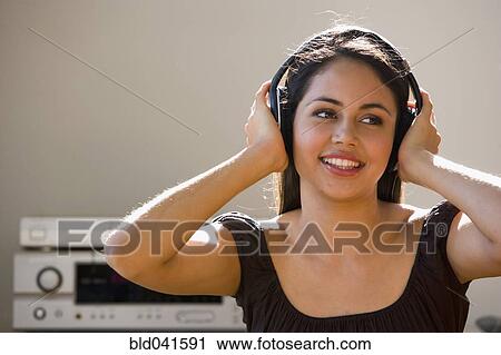 Stock Image - Young woman listening to headphones. Fotosearch