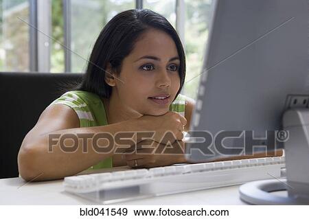 Young woman looking at computer View Large Photo Image Stock Photo - Young woman looking at computer. Fotosearch