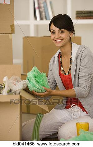Stock Photograph - Young woman packing moving boxes. Fotosearch