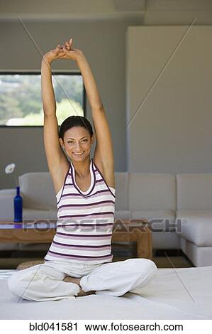 Stock Image - Young woman stretching indoors. Fotosearch
