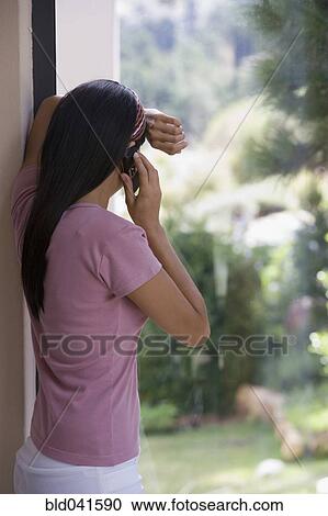 Stock Image - Young woman talking on cell phone. Fotosearch