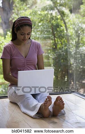 Stock Image - Young woman typing on laptop. Fotosearch