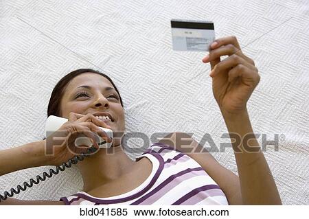 Young woman using credit card over telephone View Large Photo Image Stock Photography - Young woman using credit card over telephone. Fotosearch