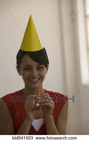 Stock Image - Young woman wearing party hat. Fotosearch